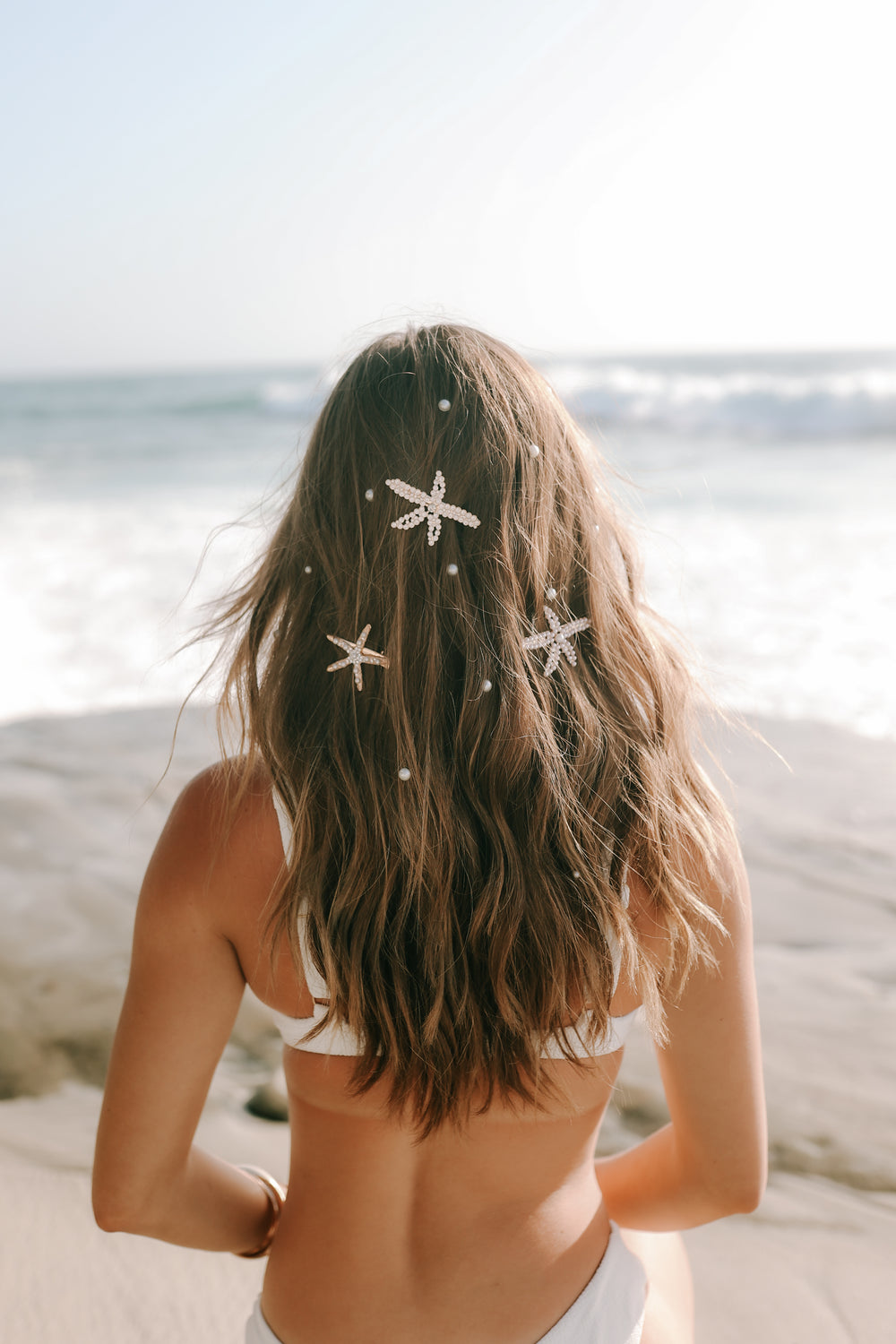 Customer with a starfish in her hair looking out to sea