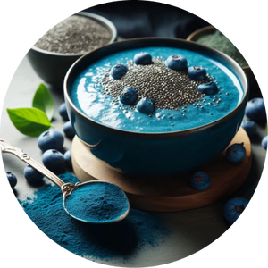 Blue smoothie bowl with chia seeds and blueberries, surrounded by fresh blueberries and a spoon of blue powder.