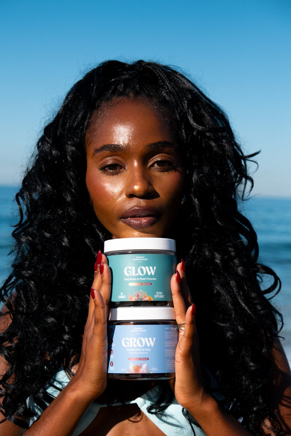 Customer holding GLOW and GROW jars against a blue sky