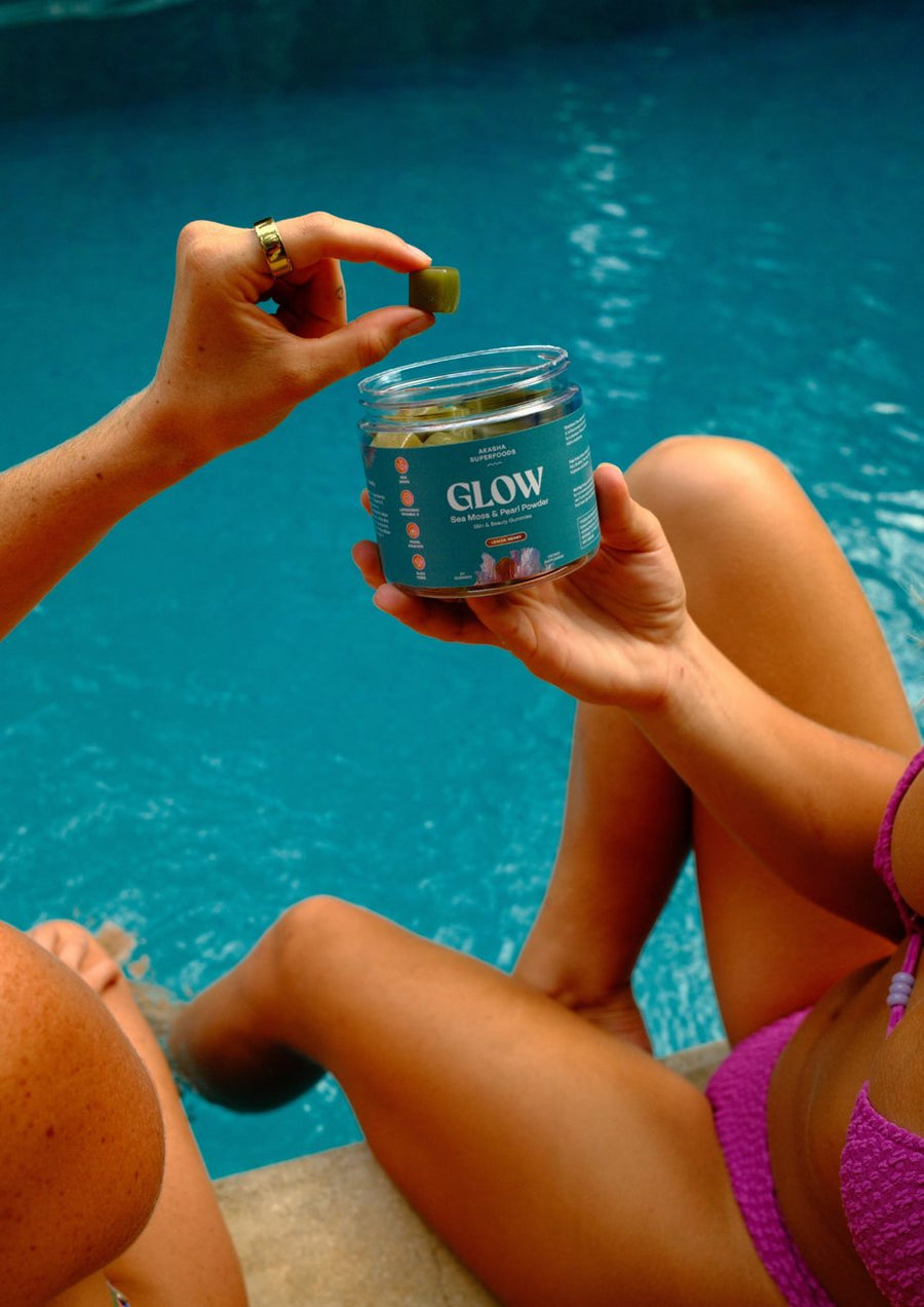 Customer holding a GLOW gummy over an open jar by the pool