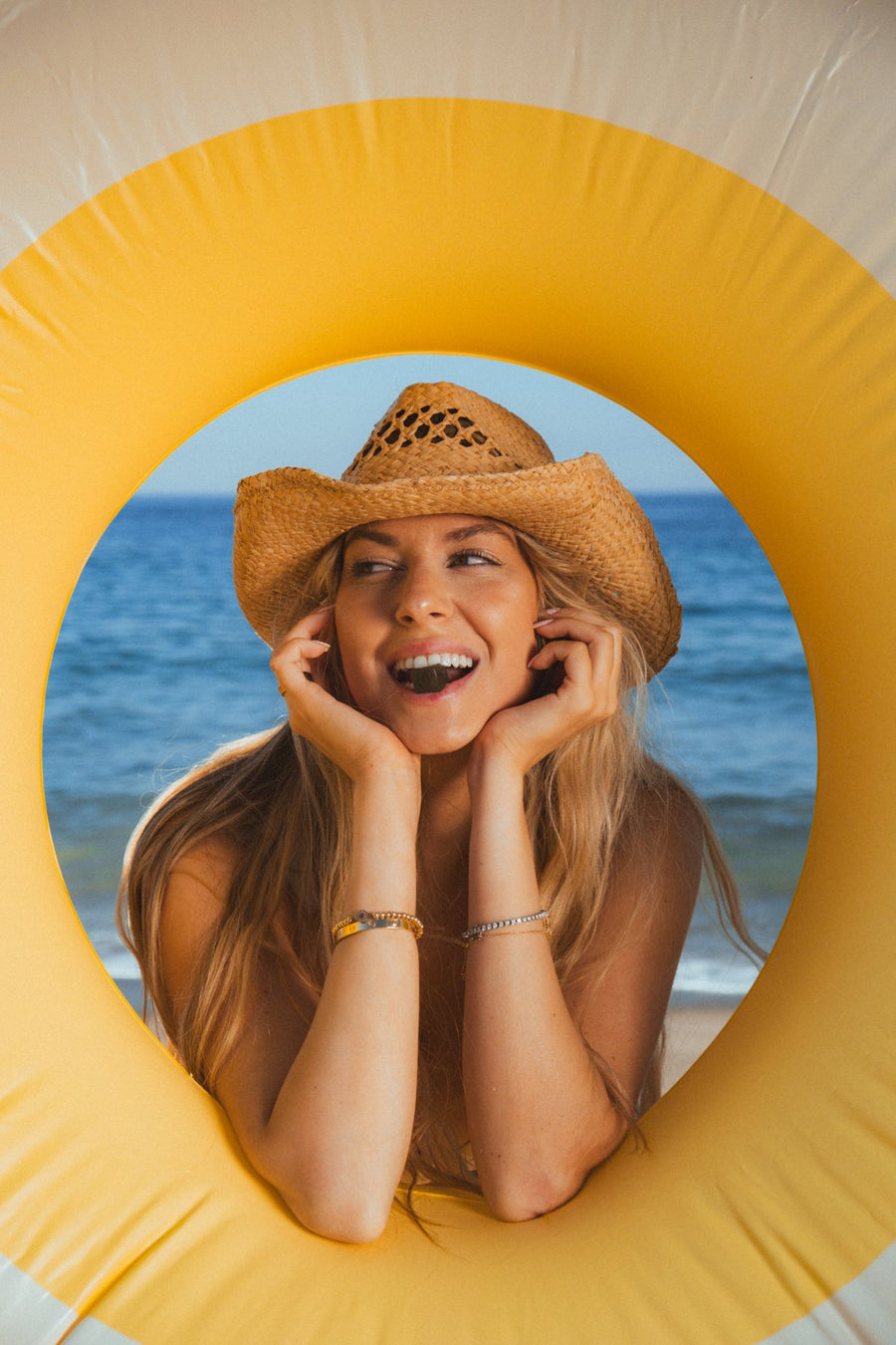 Customer laughing in a yellow pool ring on the ocean