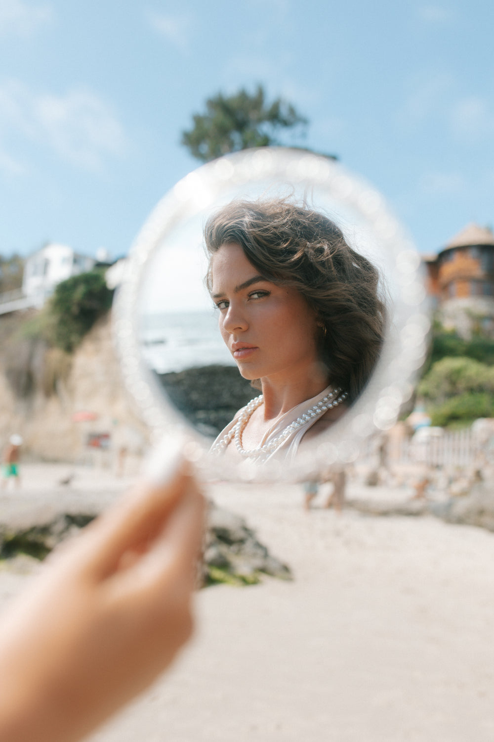 Customer on the beach checking her skin in a hand mirror